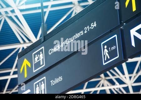 Anfahrt auf dem Schild am Flughafen - Check-in Theken und Toiletten Stockfoto