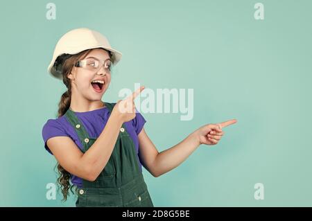 Schauen Sie hier. Kleines Mädchen in Hut spielen in der Werkstatt. Kinderschutz und Sicherheit. Kleine lächelnde Baumeister im Helm. Glückliche Kindheit. Karriere Anleitung Idee. Portrait von kleinen Mädchen mit Hut. Stockfoto