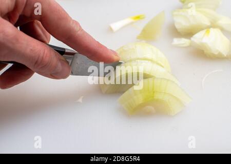 Die Hände schneiden Zwiebeln auf einem Schneidebrett. Gesunde Ernährung Konzept Stockfoto