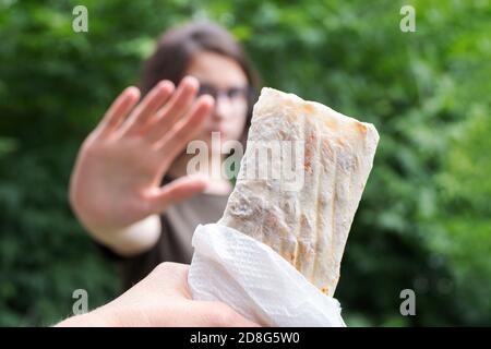 Frau auf Diät für Wellness-Konzept. Die Frau macht ein Zeichen, ihre Hand auszustrecken, um Junk Food oder Shawarma abzulehnen Stockfoto