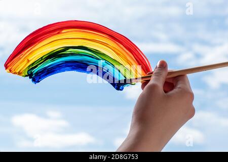 Nahaufnahme der Hand mit dem Pinsel malt den Regenbogen, das Ende der Quarantäne, die Selbstisolation, die Unterstützung der Ärzte, bleiben zu Hause Stockfoto