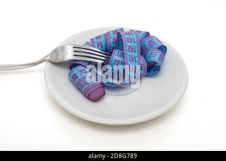 Diät und Gewichtsverlust Konzept. Blaues Maßband in weißer Platte auf Gabel auf weißem Hintergrund gewickelt Stockfoto