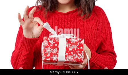 Junge Frau in roten Pullover hält verpackt Geschenk in den Händen Nahaufnahme isoliert auf Weiß Stockfoto