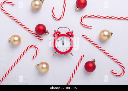 Weihnachtskomposition mit Zuckerstöcken, rotem Wecker und weihnachtskugeln auf weißem Hintergrund. Neujahrskonzept. Draufsicht - Bild Stockfoto