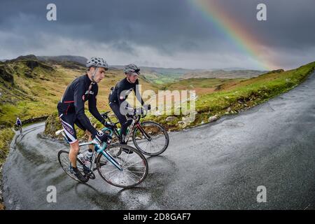 Zwei Fahrer klettern Hardknott Pass in der Fred Whitton Challenge, English Lake District, Großbritannien. Stockfoto