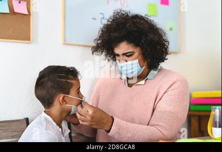 Lehrerin Frau legte Gesichtsschutzmaske an Schüler in der Vorschule Präsenzunterricht während der Corona-Virus-Pandemie - Gesundheits- und Bildungskonzept Stockfoto