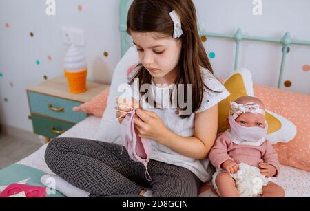 Mädchen Nähen Gesichtsmasken für sich und ihr Baby Puppe Stockfoto