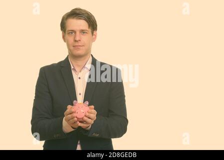 Portrait von jungen gut aussehenden Geschäftsmann in Anzug halten Sparschwein Stockfoto