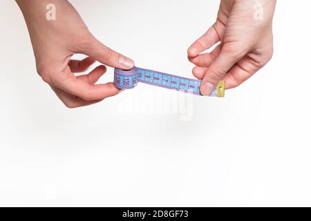 Weibliche Hände halten blau Roulette, Maßband für die Messung der Größe auf einem hellen Hintergrund, kopieren Raum Stockfoto