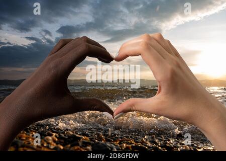 Schwarze und weiße Hände in Form von Herz isoliert auf weißem Hintergrund. Interracial Freundschaft stoppen Rassismus Konzept Stockfoto