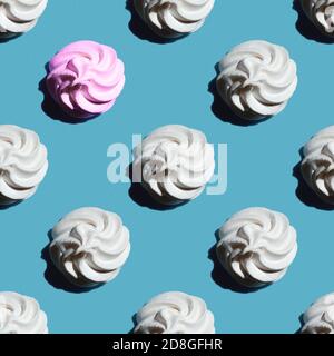 Nahtloses Muster ist eine weiße Marshmallow oder Meringue und eine Rosa Marshmallow isoliert auf einem klassischen blauen Hintergrund Stockfoto