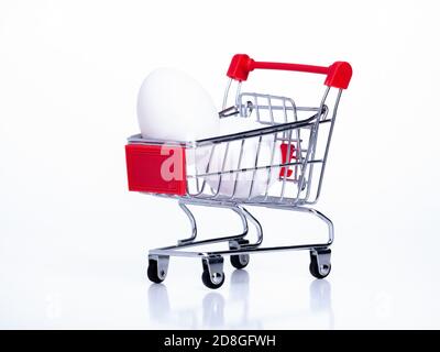 Kleiner Korb auf Rädern mit Hühnereiern auf einem Weißer Hintergrund Stockfoto