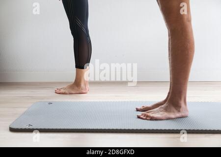 Beine von zwei Personen, die Yoga auf einer Yogamatte üben Stockfoto