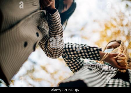 Zwei elegante Geschäftsfrauen von gemischten Rennen treffen im Freien stoßen Ellbogen statt Begrüßung mit einem Handschlag. Ellenbogen stoßen ist die neue Normalität in Pandem Stockfoto