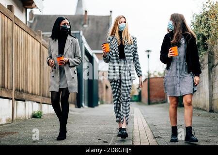 Multirassische Freunde mit Gesichtsmasken auf der Straße - Junge Millennials Mädchen, die einen freien Moment zusammen haben - Neu Normales Lifestyle-Konzept - Stockfoto