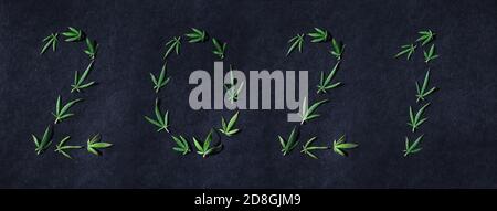 Muster von Cannabisblättern in Form von Zahlen 2021 auf dunklem Hintergrund. Das Konzept eines neuen Jahres. Hintergrund der Cannabispflanze. Speicherplatz kopieren. Der Stockfoto