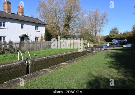 Ein Lokkeeper's Cottage am Oxford Canal mit einem Schmalboot Vor der Durchfahrt durch die Schleuse in der Nähe des Dorfes Aynho Stockfoto