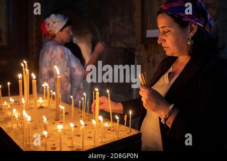 Eine Frau sagt ein Gebet, während sie eine Kerze in der Kirche Jvari anzündet, einer der heiligsten Stätten Georgiens, in Mzcheta, Georgien, Kaukasus, Europa. Stockfoto