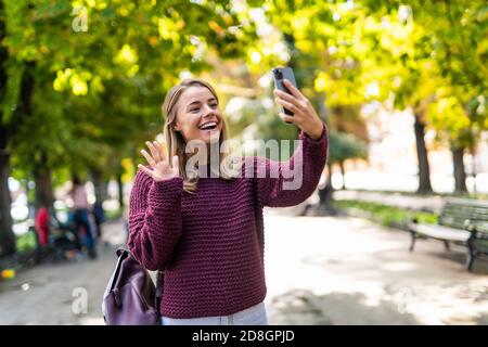 Happy girl winkende Hand Begrüßung Telefon video Anruf auf der Straße Stockfoto