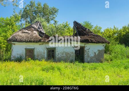 Ukrainische ländliche Landschaft mit klassischen ruiniert und verlassenen Ton ummauert Haus unter Strohdach Stockfoto