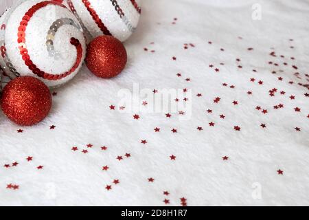 Winterurlaub, Neujahr und Dekorationskonzept. Festliches Banner mit Weihnachtsschmuck. Rote und weiße Kugeln mit rotem Konfetti auf weißem Hintergrund Stockfoto