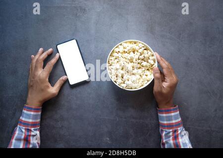 Mann Hand mit Smartphone und essen Popcorn Stockfoto
