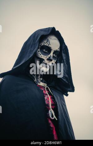 Porträt einer jungen Frau im Halloween Kostüm des Todes mit bemaltem Skelett auf ihrem Körper und Zucker Schädel Make-up. Halloween-Konzept. Stockfoto