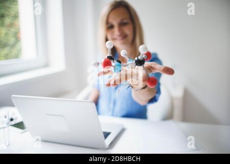 Schöne junge Frau mit molekularem Modell im modernen Büro Stockfoto