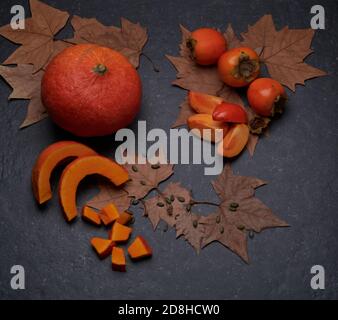 Herbstliches Gemüse und Obst: Kürbis, Kaki, geschnitten, ganz, frisch und roh Stockfoto