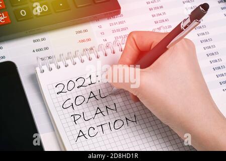 Büromitarbeiter schreibt eine Liste für 2021 in ein Notizbuch. Planungskonzept, Zielsetzung. Stockfoto