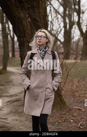 Traurige junge Frau, die im alten Herbstpark spazierengeht Stockfoto