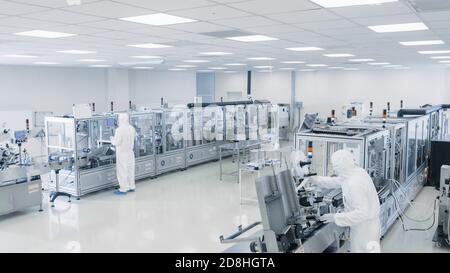 Sterile High Precision Manufacturing Laboratory wo Wissenschaftler in Protective Overall drehen sich auf Maschinen, verwenden Computer und Mikroskope, tun Stockfoto