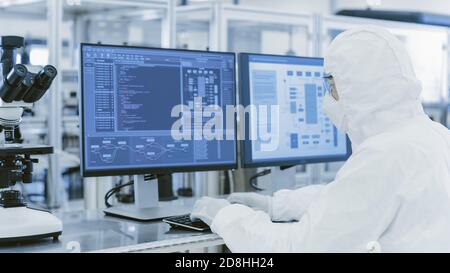 Im Labor über die Schulter Ansicht von Wissenschaftler in Schutzkleidung tun Forschung auf einem Personal Computer. Moderne Manufakturproduktion Stockfoto
