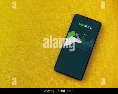 LOD, Israel - 8. Juli 2020: Upwork App Launch Screen mit Logo auf dem Display eines schwarzen Smartphone auf einem gelben Stoff Hintergrund. Draufsicht FLA Stockfoto