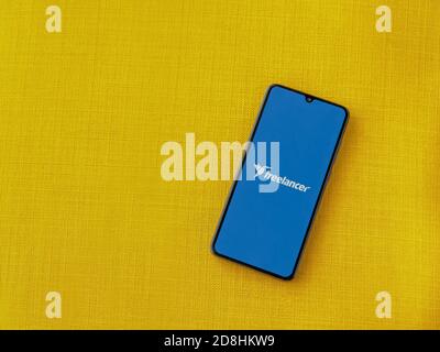LOD, Israel - 8. Juli 2020: Freiberufler App Launch Screen mit Logo auf dem Display eines schwarzen Smartphone auf einem gelben Stoff Hintergrund. Draufsicht Stockfoto