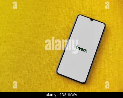 LOD, Israel - 8. Juli 2020: Fiverr App Launch Screen mit Logo auf dem Display eines schwarzen Smartphone auf einem gelben Stoff Hintergrund. Draufsicht FLA Stockfoto