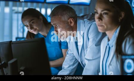 Diverse Team von Medizinern lösen Probleme und zeigen auf Computer-Bildschirme zeigt CT, MRI-Scans. Neurologen Neurowissenschaftler arbeiten im Gehirn Stockfoto