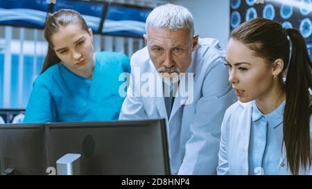 Diverse Team von Medizinern lösen Probleme und zeigen auf Computer-Bildschirme zeigt CT, MRI-Scans. Neurologen Neurowissenschaftler arbeiten im Gehirn Stockfoto