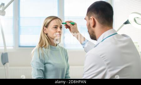 Over the Shoulder Shot eines plastischen Kosmetikchirurgen zeichnet Linien auf ein Gesicht eines schönen weiblichen Modells für die Facelift-Operation. Stockfoto