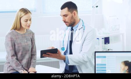 Schöne Frau besucht Arztpraxis, Er zeigt Tablet-Computer mit ihrer medizinischen Geschichte diskutieren sie ihre Gesundheit und andere medizinische Fragen. Modern Stockfoto