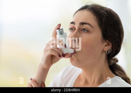 Asthma. Porträt einer jungen Frau, die Medizin inhaliert. Verschwommener Hintergrund. Speicherplatz kopieren. Stockfoto