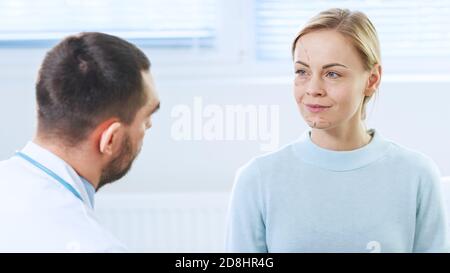 Over the Shoulder Shot eines plastischen Kosmetikchirurgen zeichnet Linien auf ein Gesicht eines schönen weiblichen Modells für die Facelift-Operation. Stockfoto