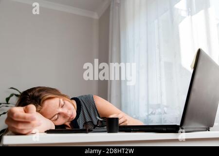 Die Frau schlief vor Müdigkeit am Arbeitstisch ein.Ansicht von unten. Speicherplatz kopieren. Konzept von Stress am Arbeitsplatz, Quarantäne und Selbstisolation während eines Pandem Stockfoto