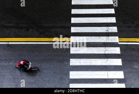 Draufsicht auf Gentleman Radfahrer auf dem Fahrrad hinunter Straße in der Nähe von Crosswalk während regnerischen Tag - tägliche Lifestyle urban Ruhende Konzept - Noir urban styl Stockfoto