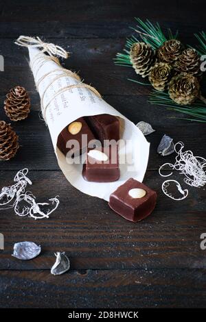 Lebkuchenwürfel mit Schokoladeneiser in einem Papierbeutel, verziert mit Kiefernzweig, und einem Ausstechelch Stockfoto