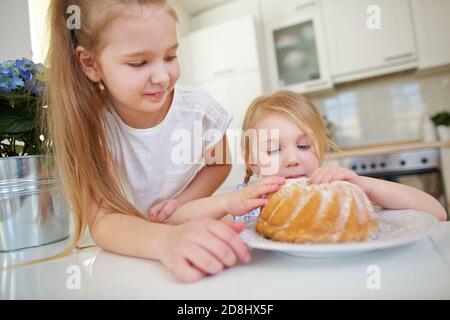 Zwei Kinder essen auf einem frischen Kuchen in der Küche Stockfoto