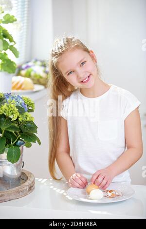 Kind lächelt, während es ein Ei in der Küche schält Stockfoto