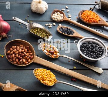 Leguminosen Pulse Vielfalt flach lag auf blauen Tischhintergrund. Kugeln, Schüsseln und Schöpflöffel mit trockener vegetarisch gesunder Nahrung. Stockfoto