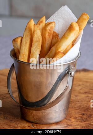 Pommes Frites in einem kleinen Metalleimer mit Serviette serviert. Vertikale Ansicht. Stockfoto