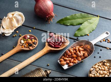 Leguminosen Pulse Vielfalt flach lag auf blauen Tischhintergrund. Kugeln, Schüsseln und Schöpflöffel mit trockener vegetarisch gesunder Nahrung. Stockfoto